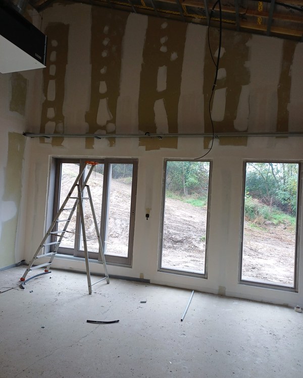 Une pièce en cours de finition, avec ses grandes baies vitrées